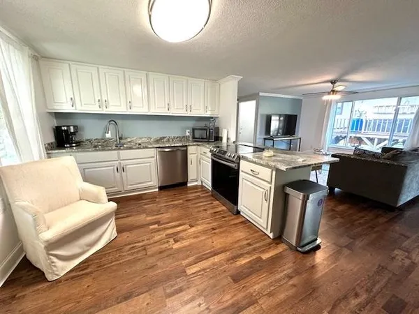 a kitchen with a stove top oven a sink dishwasher and a dining table with wooden floor