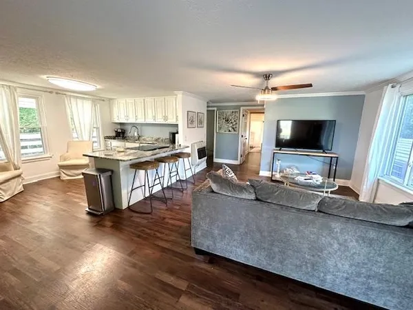 a living room with stainless steel appliances granite countertop furniture and a flat screen tv