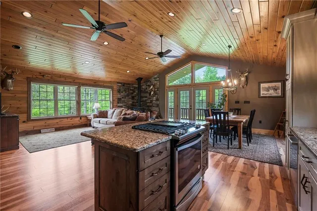 a kitchen with stainless steel appliances granite countertop a stove top oven a dining table and chairs with wooden floor