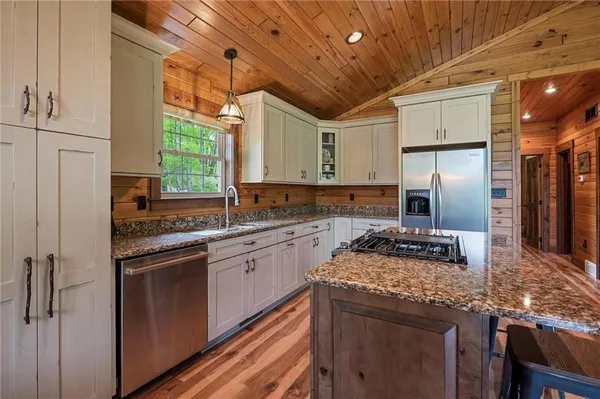 a kitchen with stainless steel appliances granite countertop a sink a stove and a refrigerator