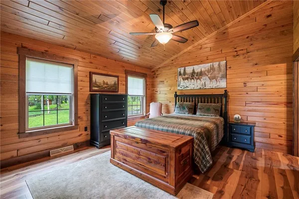 a bedroom with a bed a flat tv screen and dresser
