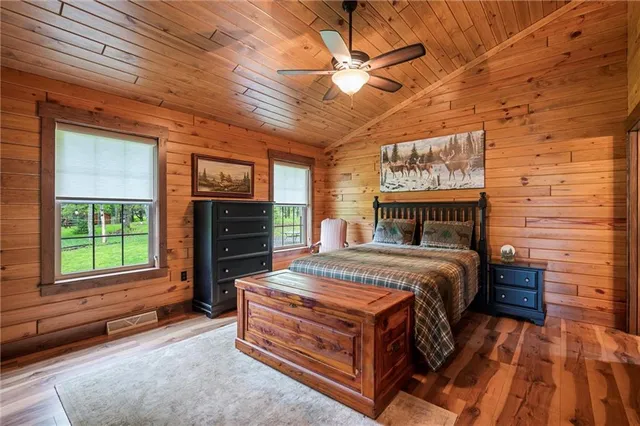 a bedroom with a bed a flat tv screen and dresser