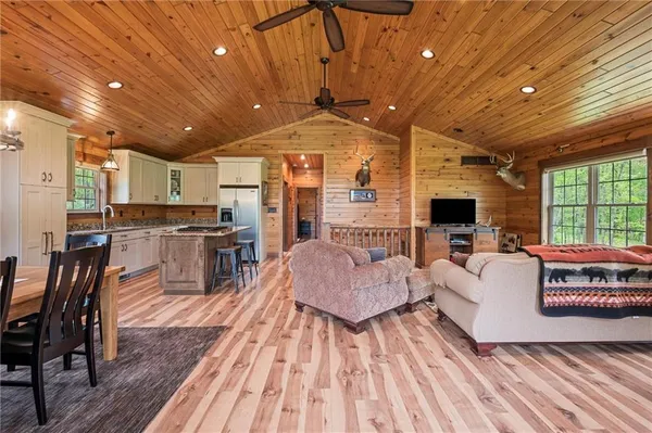 a living room with stainless steel appliances furniture a flat screen tv and a table