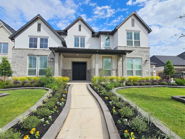 a front view of a house with a yard and potted plants