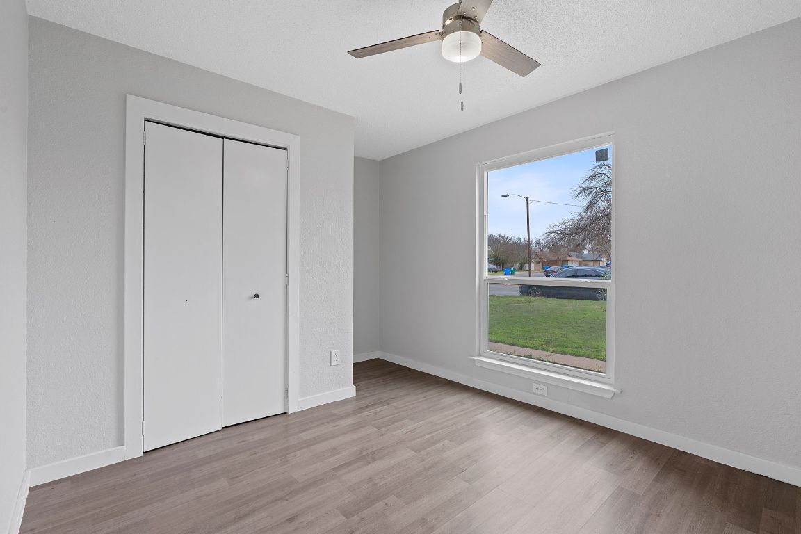 16131 Stoneham Circle Pflugerville, TX 78660 - Photo 14 of 19 an empty room with wooden floor fan and windows