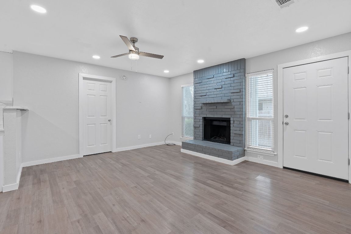 16131 Stoneham Circle Pflugerville, TX 78660 - Photo 3 of 19 an empty room with wooden floor fireplace and windows