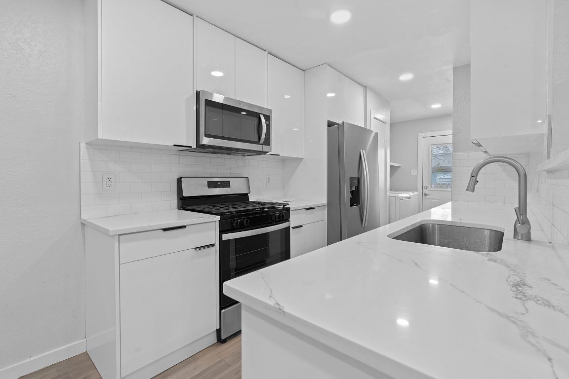 16131 Stoneham Circle Pflugerville, TX 78660 - Photo 5 of 19 a kitchen with stainless steel appliances a microwave a sink and a refrigerator