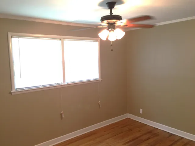 a view of a room with wooden floor fan and windows