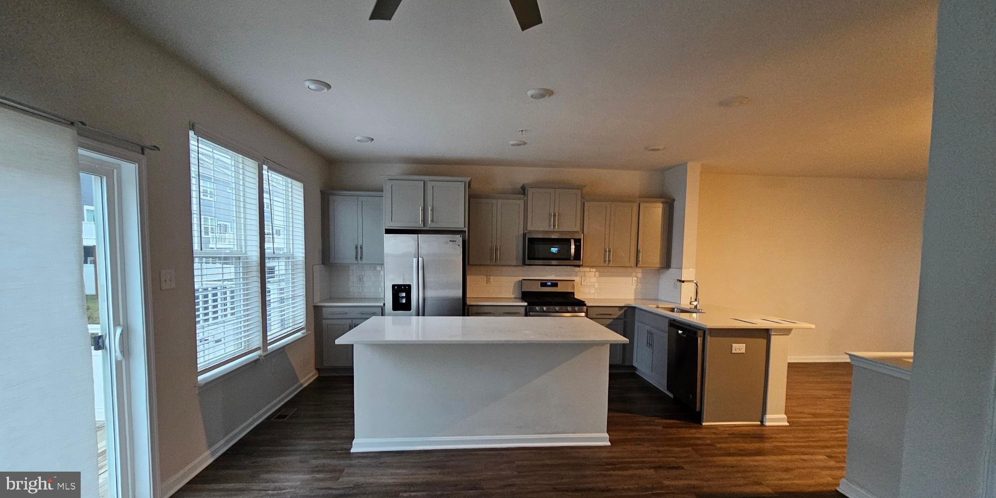 5147 Constitution Street Frederick, MD 21703 - Photo 6 of 23 a view of a kitchen with kitchen island a counter top space a sink wooden floor and a large window