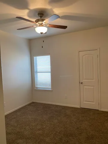 an empty room with a ceiling fan and window