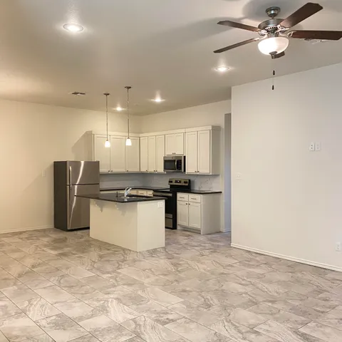 a large kitchen with stainless steel appliances kitchen island granite countertop a refrigerator and a sink