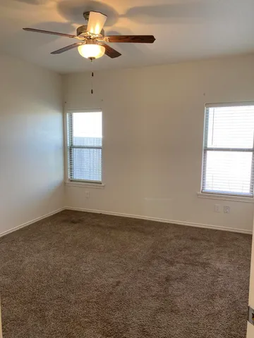 an empty room with a window and a fan