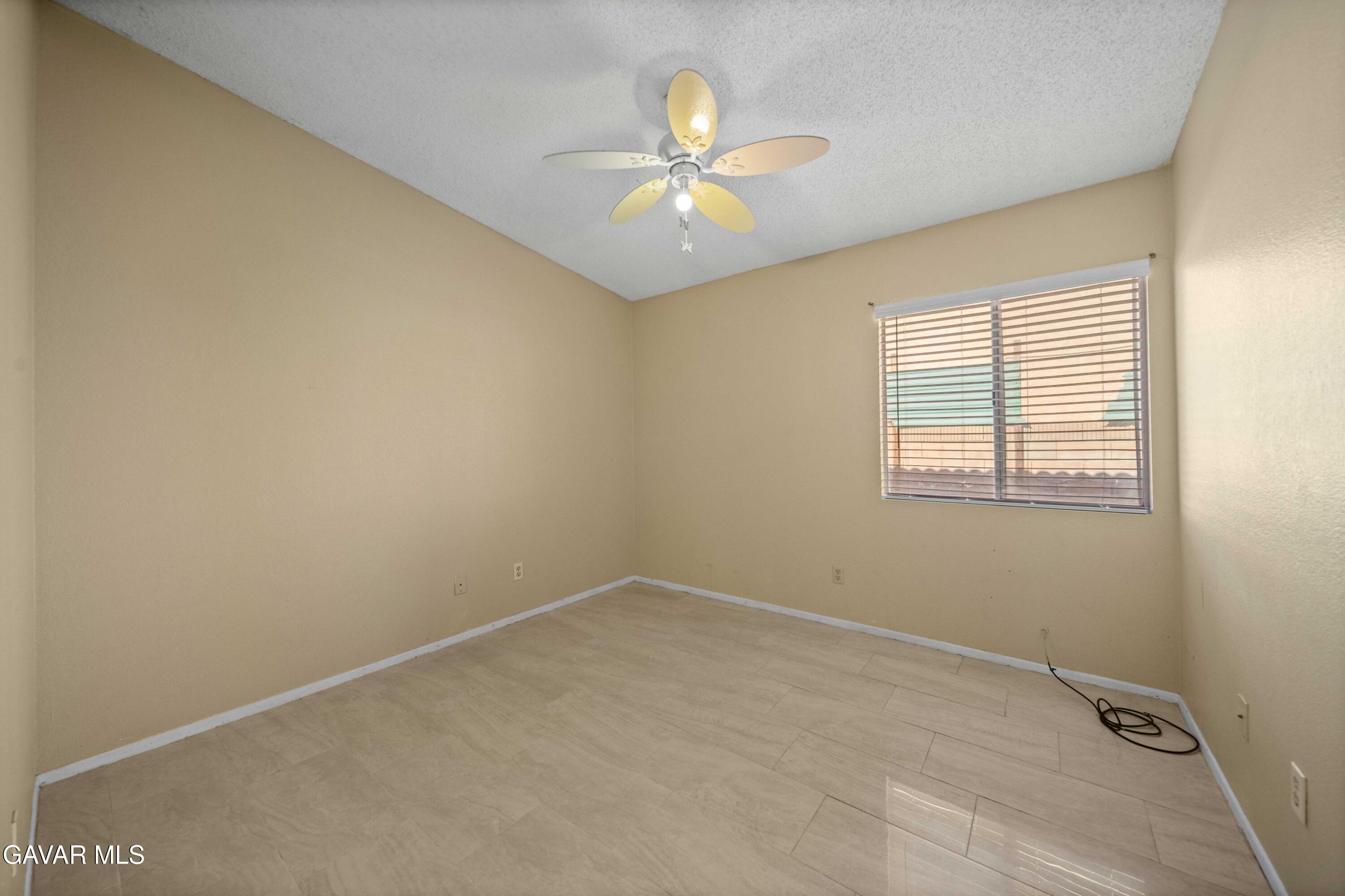 43815 Silver Bow Road Lancaster, CA 93535 - Photo 11 of 20 an empty room with a window and a ceiling fan