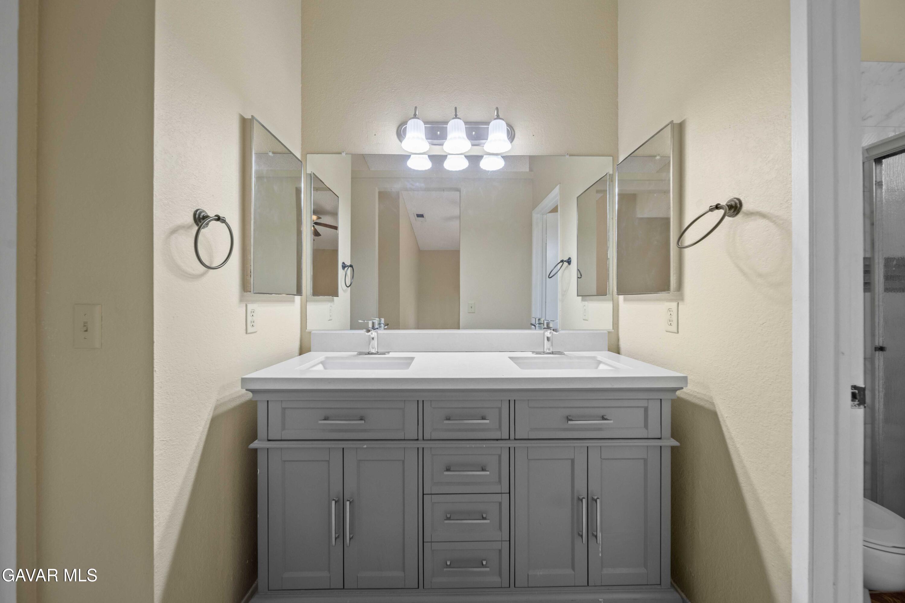 43815 Silver Bow Road Lancaster, CA 93535 - Photo 16 of 20 a bathroom with a granite countertop sink a large mirror and a