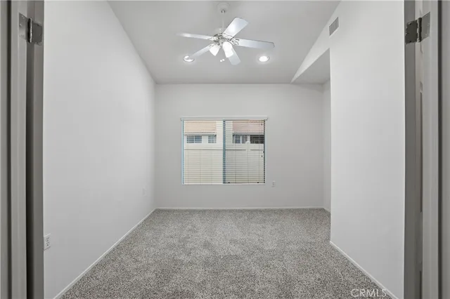 an empty room with a chandelier fan and windows