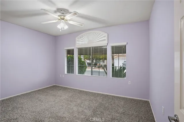 an empty room with windows and ceiling fan