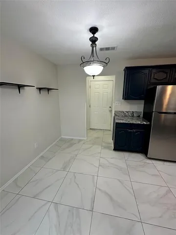 a kitchen with granite countertop a refrigerator and a cabinets