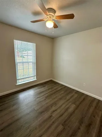 a view of an empty room with window and wooden floor