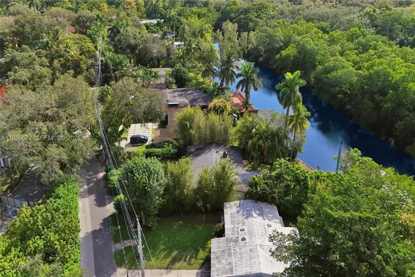 an aerial view of residential house with outdoor space and trees all around