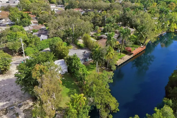 an aerial view of a residential houses with outdoor space and trees all around