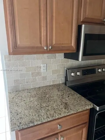 a kitchen with granite countertop white cabinets and stainless steel appliances