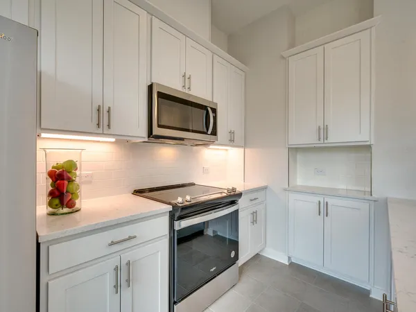 a kitchen with stainless steel appliances granite countertop white cabinets and a stove