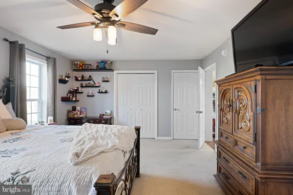 a bedroom with a bed and a flat tv screen on dresser