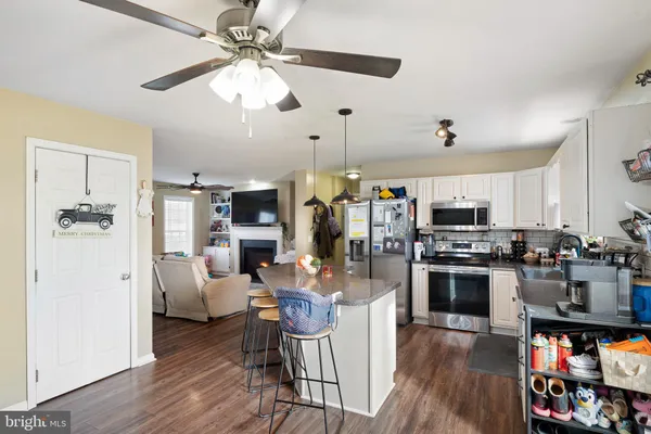 a living room with stainless steel appliances kitchen island granite countertop furniture a rug and a view of kitchen