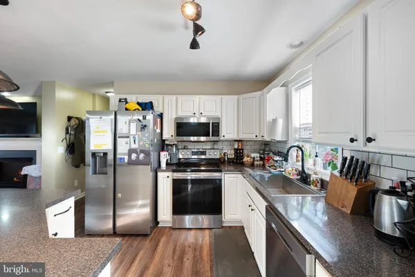 a kitchen with stainless steel appliances granite countertop a refrigerator a stove top oven a sink and dishwasher
