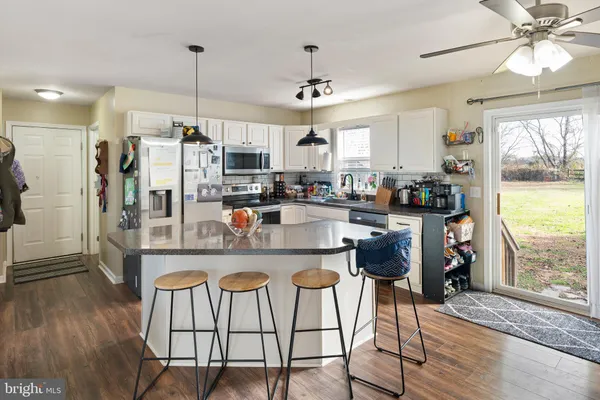 a kitchen with stainless steel appliances kitchen island granite countertop a table chairs and a refrigerator