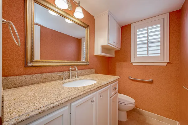 a bathroom with a granite countertop toilet a sink and a mirror