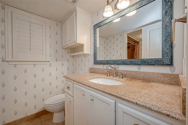 a bathroom with a granite countertop toilet sink and mirror