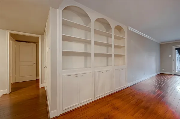a view of an empty room with wooden floor and closet