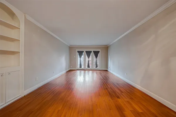 a view of an empty room with wooden floor and cabinets