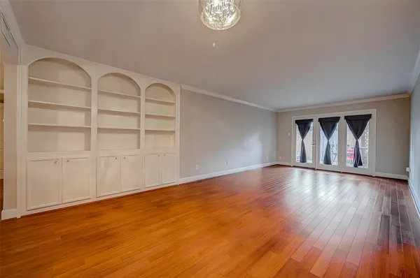a view of an empty room with wooden floor and window