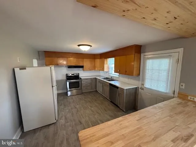 a kitchen with stainless steel appliances kitchen island granite countertop a refrigerator a sink a stove and oven