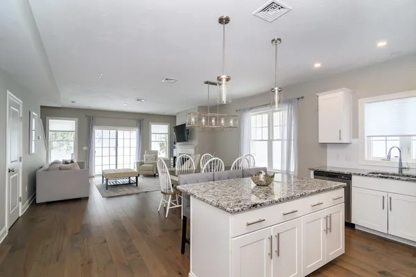 a kitchen with granite countertop a stove and white cabinets with wooden floor