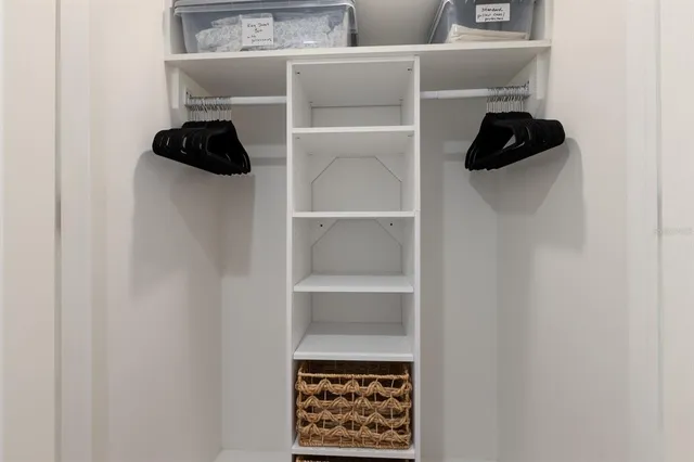 a close view of walk in closet with clothes and shoes