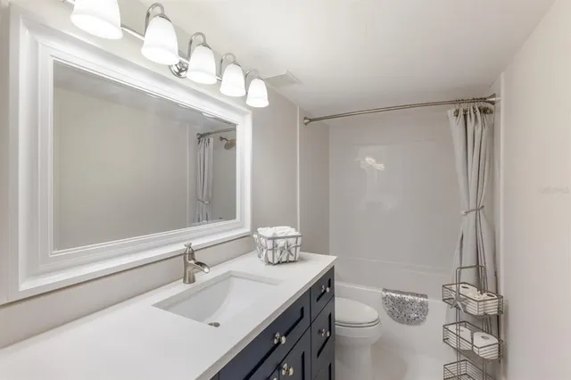 a bathroom with a sink a toilet a mirror and shower