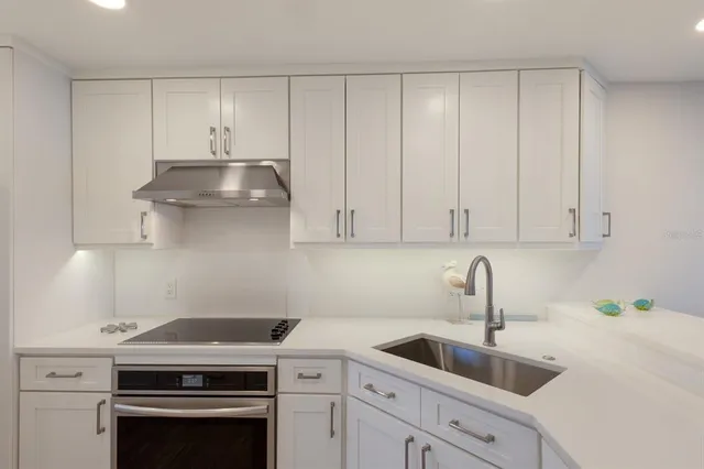 a kitchen with granite countertop a sink a stove and cabinets