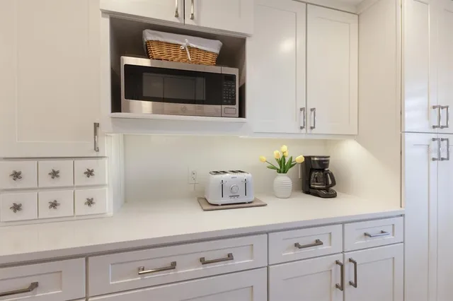 a kitchen with white cabinets and sink