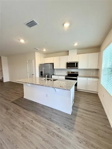 a large kitchen with stainless steel appliances granite countertop a stove a sink and a refrigerator