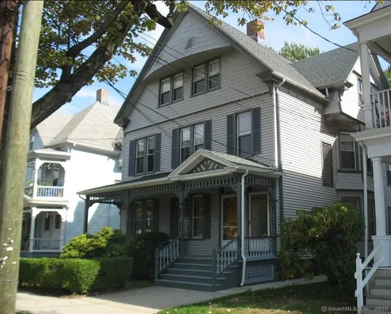 a view of a white house with large windows and a small yard