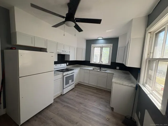 a kitchen with a refrigerator a sink dishwasher a stove and white cabinets with wooden floor