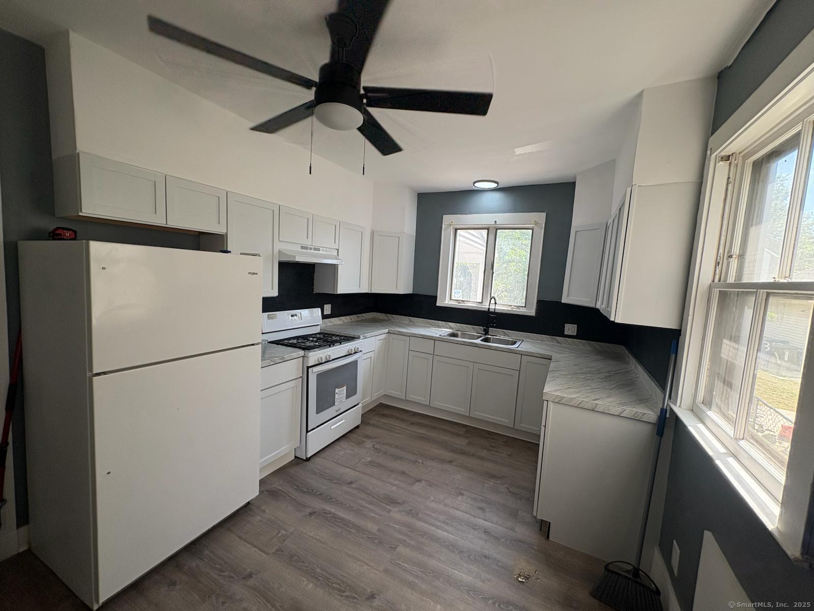319 Sherman Avenue New Haven, CT 06511 - Photo 9 of 19 a kitchen with a refrigerator a sink dishwasher a stove and white cabinets with wooden floor