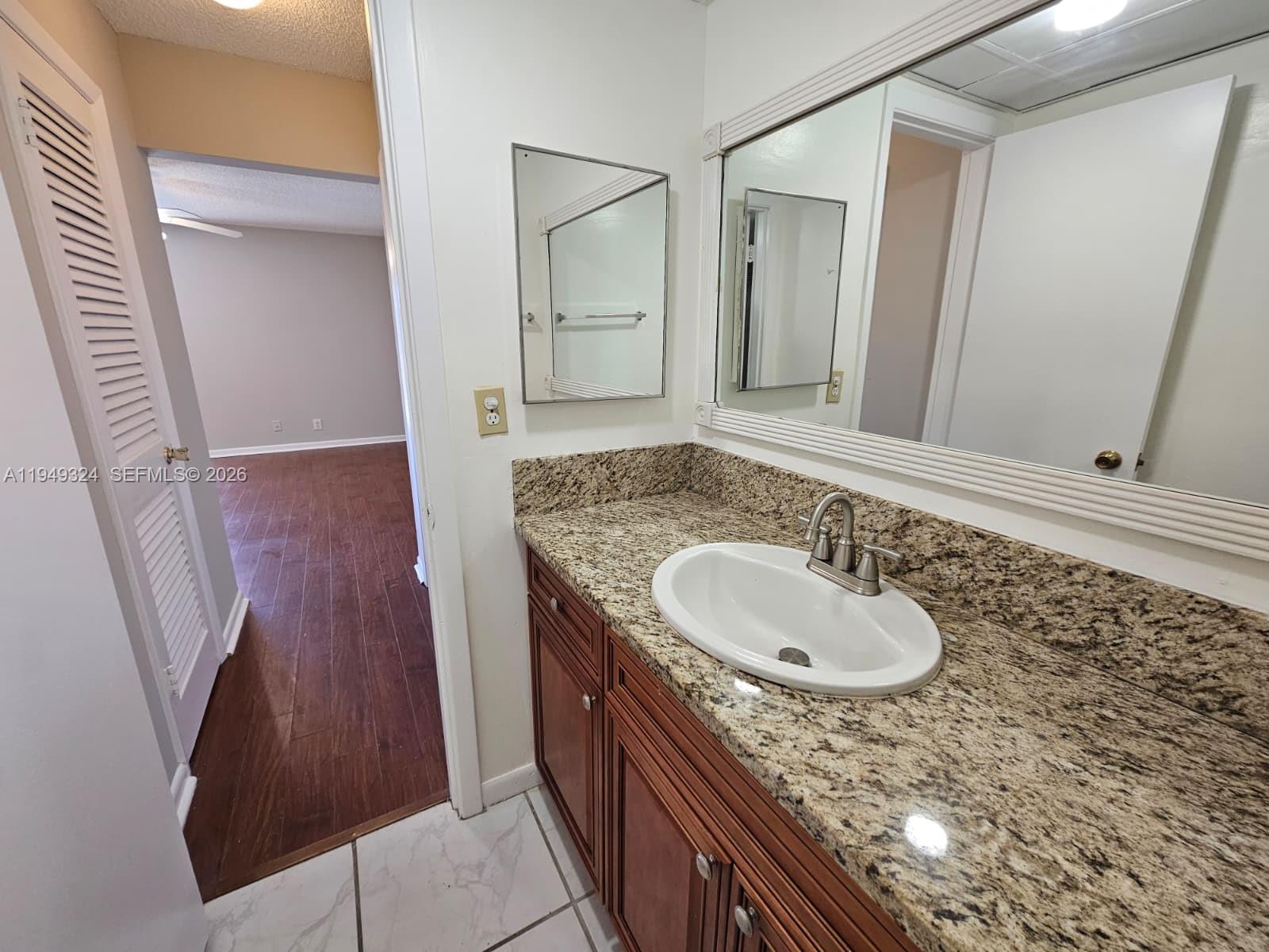 642 Northwest 13th Street, Unit 310 Boca Raton, FL 33486 - Photo 18 of 32 a bathroom with a granite countertop sink a mirror and a shower