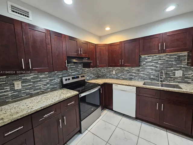 a kitchen with stainless steel appliances granite countertop a refrigerator and a stove top oven