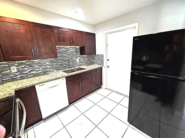 a kitchen with granite countertop a stove a sink and a microwave