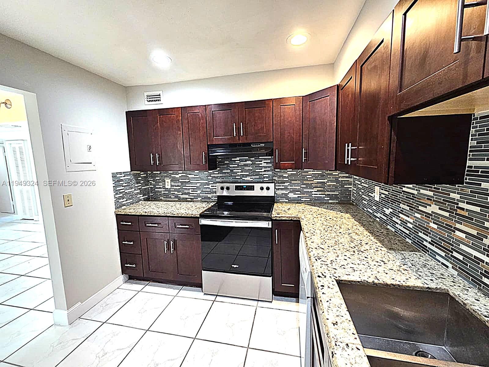 642 Northwest 13th Street, Unit 310 Boca Raton, FL 33486 - Photo 9 of 32 a kitchen with granite countertop a stove a sink and a microwave