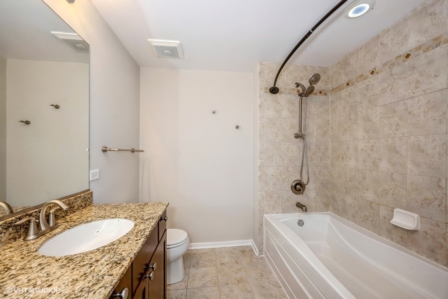 520 South State Street, Unit 702 Chicago, IL 60605 - Photo 12 of 20 a bathroom with a granite countertop sink a mirror a bathtub and shower